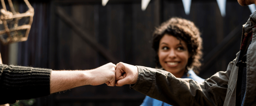 Woman smiling while two men are sharing a fist bump; vinyl flooring