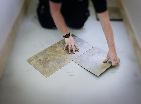 Man on knees doing LVT floor laying